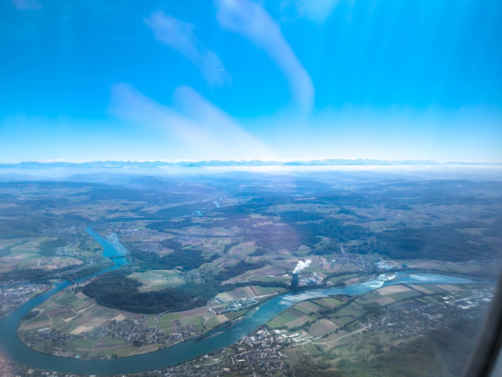 High altitude aerial view from aircraft window showing river meander and landscape during transit