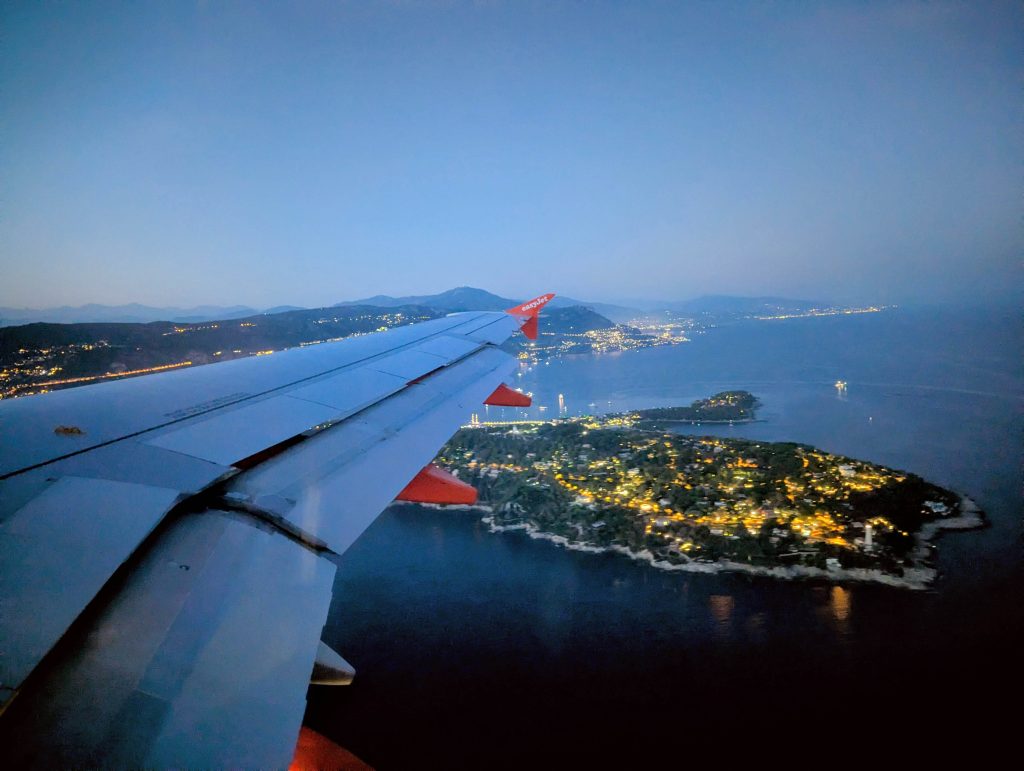 Aerial view of the Cote d Azur coastline and Cap Ferrat at dusk with city lights approaching Nice airport
