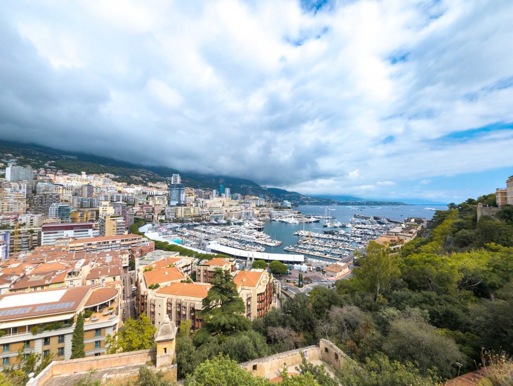 Elevated panoramic view of Port Hercule in Monaco filled with luxury yachts and bordered by Monte Carlo skyscrapers