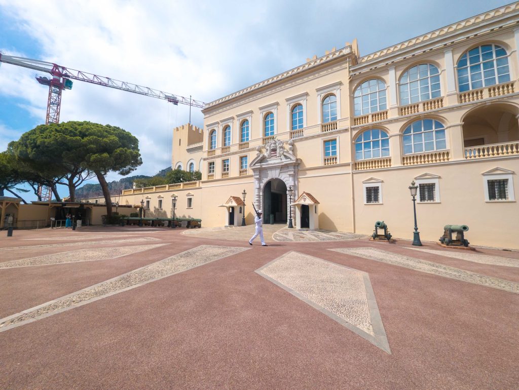 Palais Princier courtyard in Monaco with ceremonial cannons and a palace guard marching in white uniform
