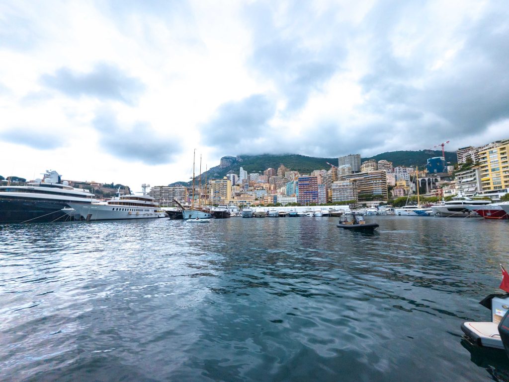 Superyachts moored along the quay at Port Hercule in Monaco with city towers rising along the hillside