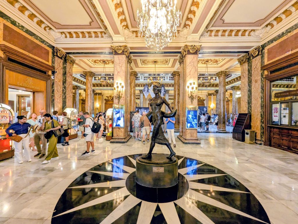 Opulent marble atrium lobby of the Casino de Monte Carlo adorned with classical columns and crystal chandeliers