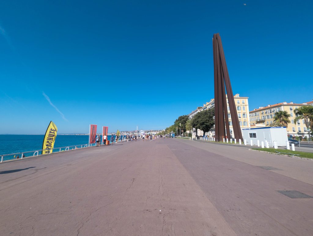 Promenade des Anglais in Nice with the curved steel monument overlooking palm trees and the Mediterranean Sea