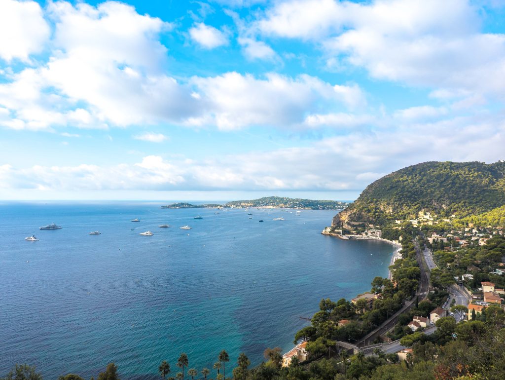 Elevated coastal view overlooking the turquoise bay of Eze sur Mer dotted with yachts and coastal railway tracks