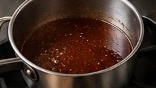 Red wine and beef stock reduction simmering gently in stainless steel saucepan