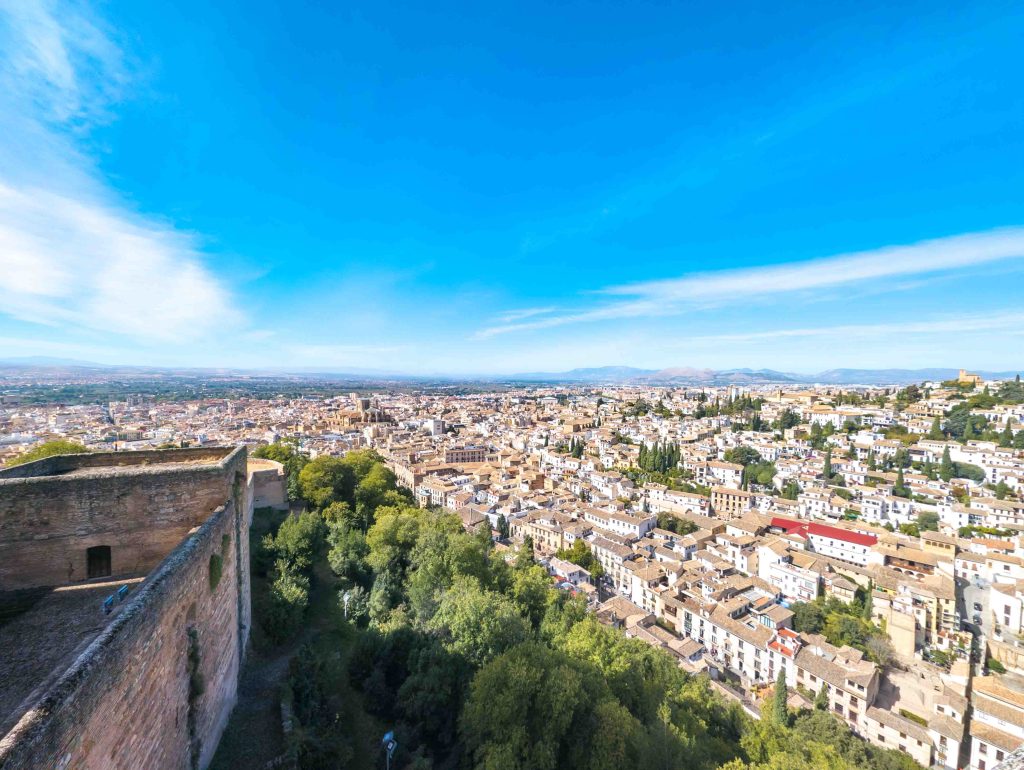 Sweeping view from the stone ramparts of the Alcazaba fortress overlooking the historic center of Granada and distant mountain peaks
