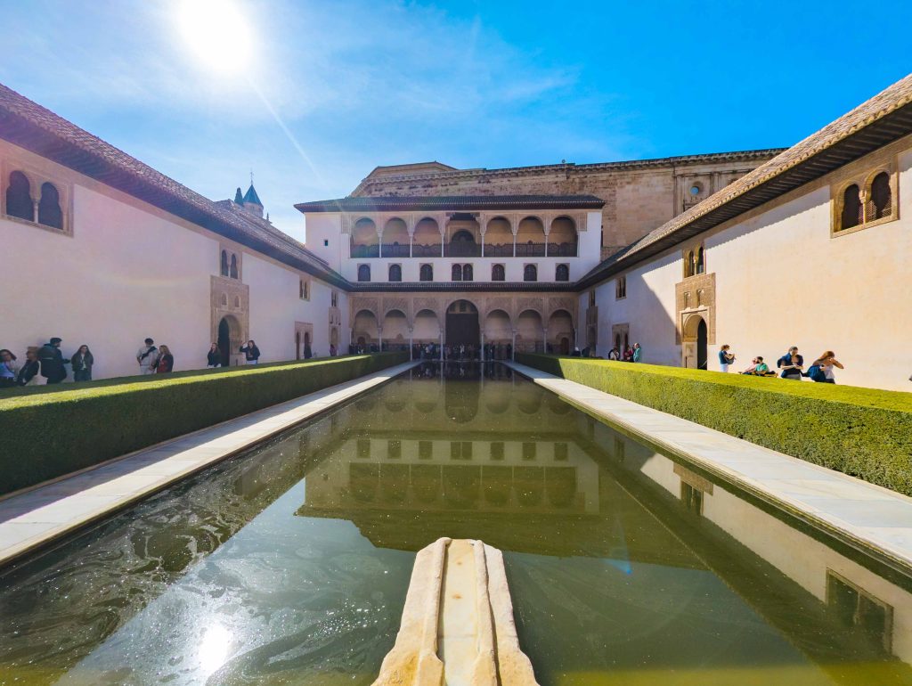 Long reflecting pool flanked by trimmed myrtle hedges in the Court of the Myrtles with the Renaissance facade of the Palace of Charles V behind